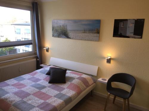 een slaapkamer met een bed, een stoel en een raam bij Haus Solymar App. 59 in Grömitz