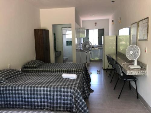 a bedroom with a bed and a desk with a fan at Suítes em Capitolio in Capitólio