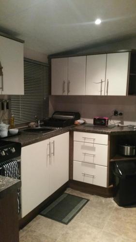 una cocina con armarios blancos y fregadero en crimdon dene holiday park en Hartlepool