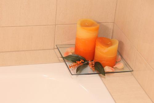 a glass holder with two orange candles on a counter at Apartamento Oronoz in Oronoz-Mugaire