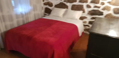 a bedroom with a bed with a stone wall at Dona Gracia Belmonte in Belmonte