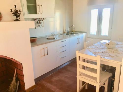 uma cozinha com armários brancos, uma mesa e um lavatório em Casa do Chaparral campo e praia em Cercal