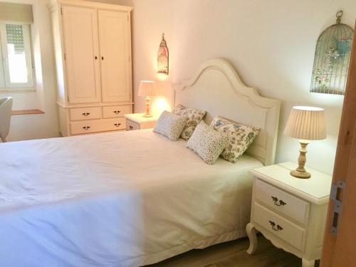 una camera da letto con un grande letto bianco con cuscini di Casa do Chaparral campo e praia a Cercal