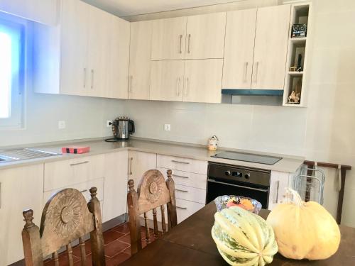 a kitchen with white cabinets and a table with a pumpkin at Casa do Chaparral campo e praia in Cercal