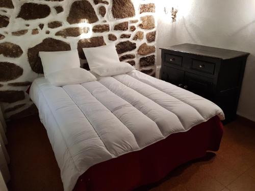 a bed in a room with a stone wall at Dona Gracia Belmonte in Belmonte