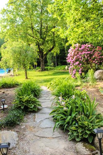 a stone path in a park with flowers and trees at The Nutmeg Inn in Meredith