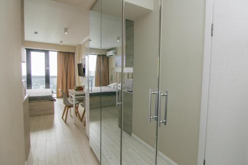 a bathroom with a glass shower and a bedroom at Swiss Quality Apartments (Beach Tower) in Batumi