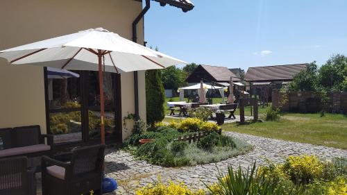 a patio with an umbrella and tables and chairs at Pokoje i domki Saraceńska Chata in Stegna