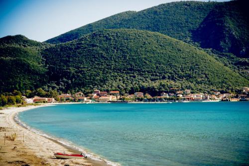a beach with a boat on the sand and mountains at Seafront Luxury residence with amazing view in Vasiliki