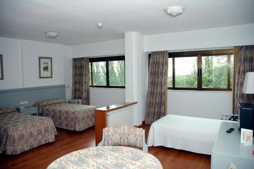 a hotel room with two beds and a desk at Hotel Escuela Madrid in Madrid