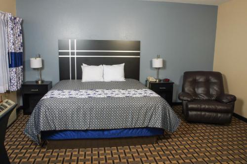 a bedroom with a bed and a leather chair at DUTCH INN AND SUITES in Orange City