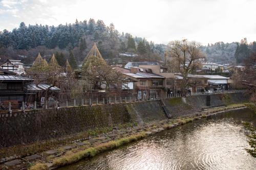 a river in a town with houses and trees at Hidatakayama Futarishizuka Hakuun in Takayama
