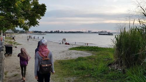 a couple of people walking down a beach at Tokido Private Water Chalet PD in Port Dickson