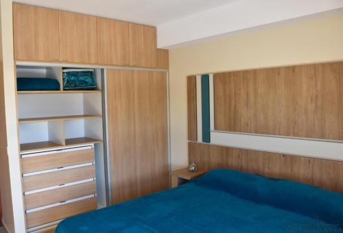 a bedroom with a blue bed and wooden cabinets at Malvinas Departamentos in San Rafael