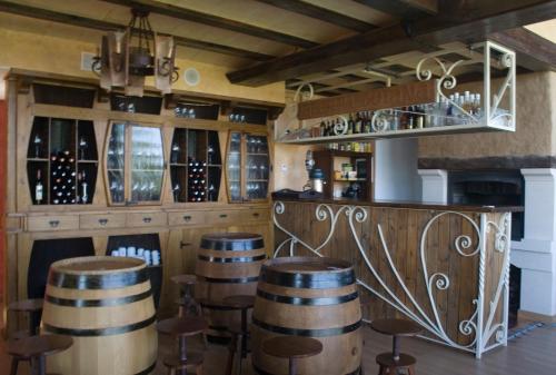 a bar with wooden barrels and a bunch of wine bottles at Hotel Rural y SPA Kinedomus Bienestar in Aranda de Duero