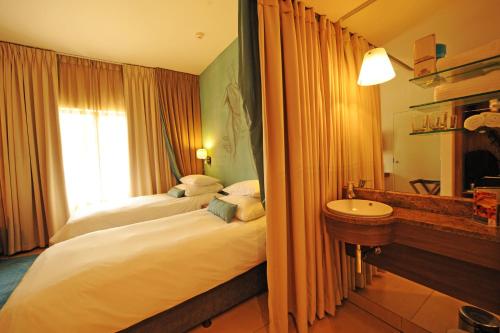 a hotel room with two beds and a sink at Metcourt at Emperors Palace in Kempton Park