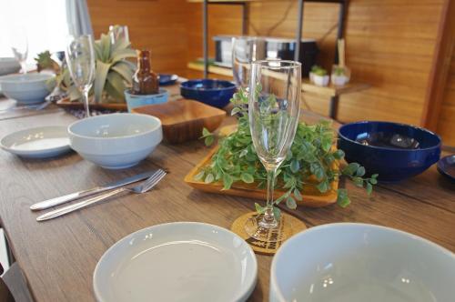 a wooden table with plates and glasses on top of it at Villent Kujukuri Arrow in Kujukuri