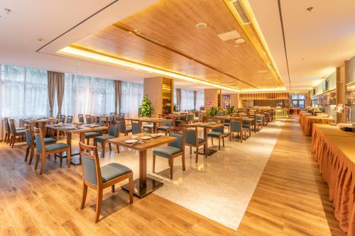 um restaurante com mesas e cadeiras de madeira e janelas em Chengdu Jiuzhaigou Hotel em Chengdu