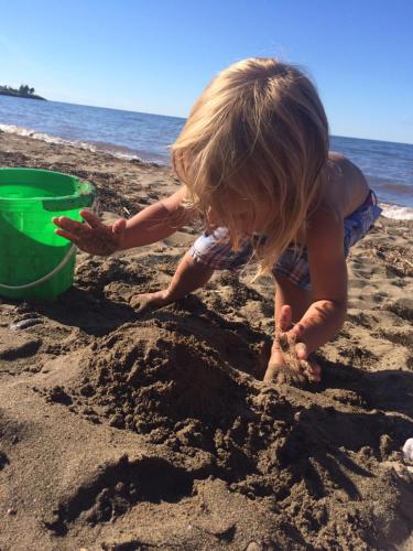 a little girl playing in the sand on the beach at The Coastal Cabins in New Brunswick in Cape Tormentine
