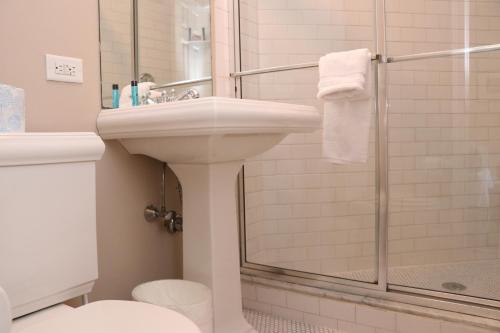 Un baño blanco con lavabo y ducha. en Stylish Downtown Studio, #32, en Boston