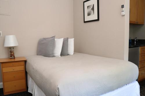 a bedroom with a white bed with a nightstand and a bed sidx sidx sidx at Stylish Downtown Studio, #32 in Boston