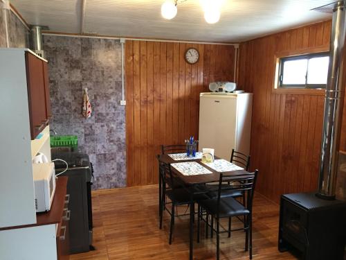 y cocina con mesa, sillas y nevera. en Cabaña Centro Pitrufquen, en Pitrufquén