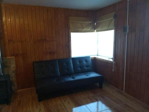 a black leather couch in a room with a window at Cabaña don Lalo Pitrufquen in Pitrufquén