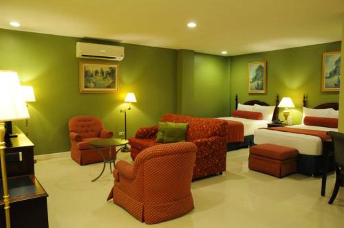 a hotel room with two beds and chairs at Dreamwave Hotel Santiago in Santiago City