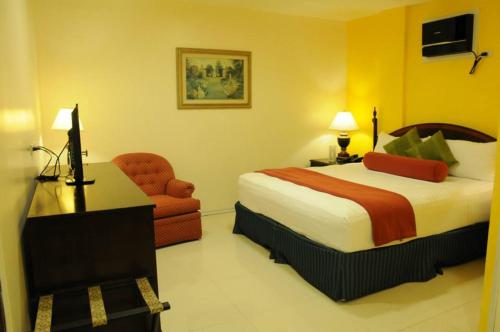 a hotel room with a bed and a chair at Dreamwave Hotel Santiago in Santiago City
