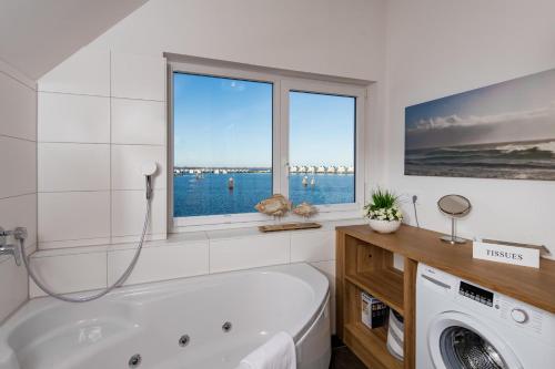 a white bathroom with a tub and a window at Maine in Olpenitz