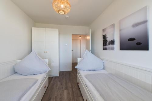 a white room with two beds and a chandelier at Baltic Breeze in Olpenitz