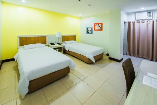 a hotel room with two beds and a table at L'Fisher Ecotel in Bacolod