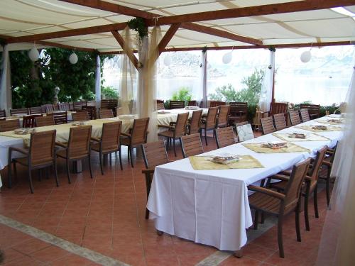 eine Reihe von Tischen und Stühlen mit weißen Tischdecken in der Unterkunft Pansion Laguna in Metajna