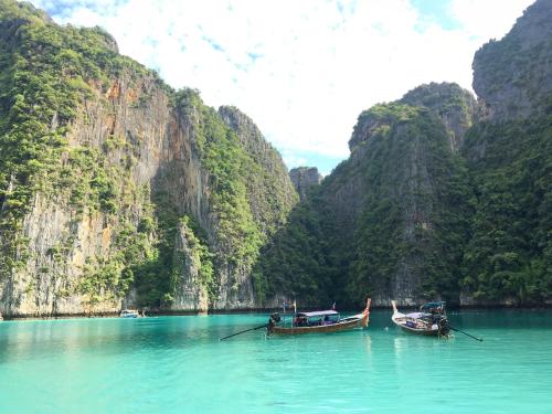 two boats sitting in the water in front of mountains at Phi Phi Maiyada Resort in Phi Phi Don