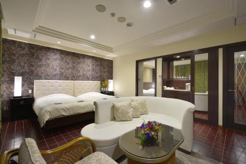 a bedroom with a bed and a couch and a table at EXES Ishigaki in Ishigaki Island