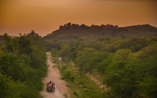 a truck driving down a dirt road with a castle on a hill at Ramathra Fort in Sapotra