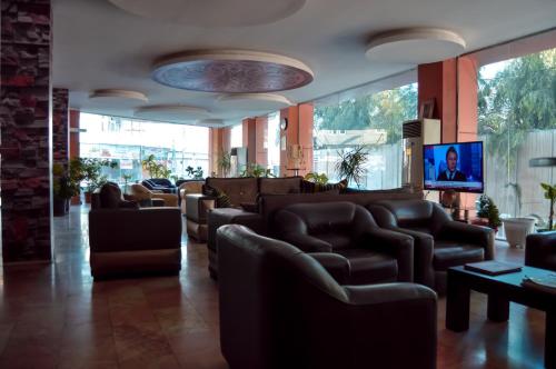 a waiting room with leather chairs and a flat screen tv at Fareeq Hotel in Erbil