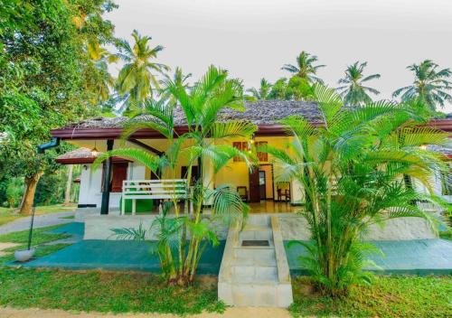 a house with palm trees in front of it at The Berrycove Bungalow in Kurunegala
