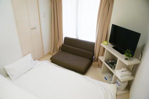 um pequeno quarto com uma cama e uma televisão em Ocean Trusty Residence Tennoji East em Osaka
