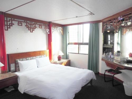 a bedroom with a large white bed and a desk at Modern Plaza Hotel in Kaohsiung