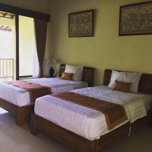 two beds in a hotel room with at Raka Rai Bungalows in Ubud