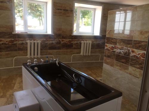 uma casa de banho com um lavatório preto e 2 janelas em Sanatorium Naroch em Lago Naroch