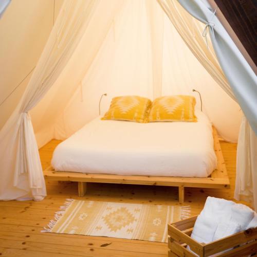 a bed in a tent with two pillows on it at HolaCamp Sitges Garrofer in Sitges