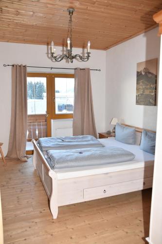 a bedroom with a large bed with a chandelier at Ferienwohnungen Bauernhof Andreas Kleiner in Tannheim