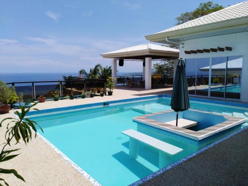 una piscina con ombrellone accanto a una casa di Seaview Mansion Dalaguete Apartment 4 -Family a Dalaguete