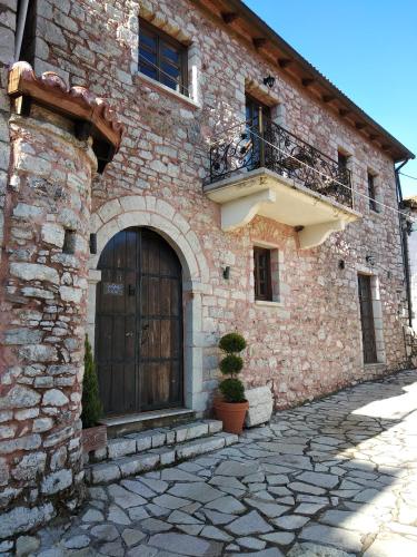 a brick building with a wooden door and a balcony at Proselinos in Dhimitsana