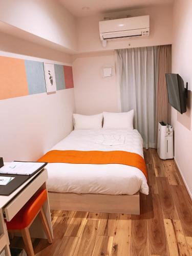 a small room with a bed and a desk and a computer at SARASA HOTEL Shinsaibashi in Osaka