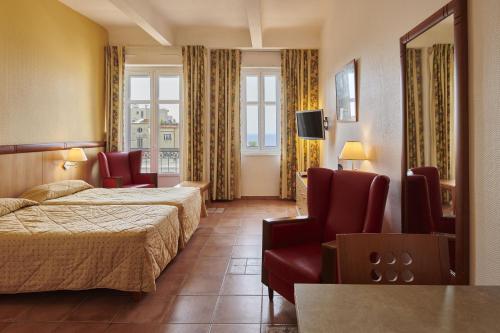 um quarto de hotel com duas camas e cadeiras e uma televisão em Residence Vacances Bleues le Mediterranée em Saint-Raphaël