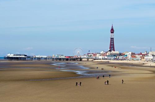 a group of people walking on a beach with a pier at Simpson Beach View Apartments by Blackpool Service Apartments in Blackpool