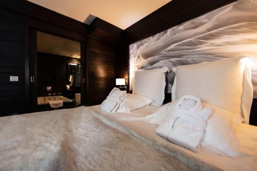 um quarto com uma cama com toalhas brancas em Avenue Lodge Hotel & Spa em Val dʼIsère